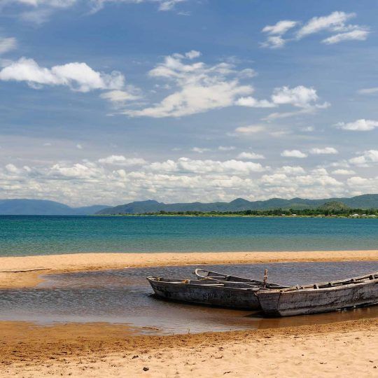 19968515 - tanzania, tanganyika lake  is the worlds longest and second deepest fresh water lake, it is also one of the oldest lakes on the planet  the picture presents beautiful sand beach and traditional boats